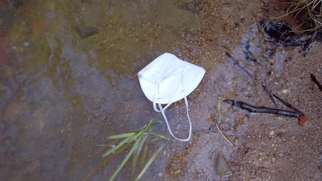 丢弃的FFP2口罩漂浮在小溪上视频素材