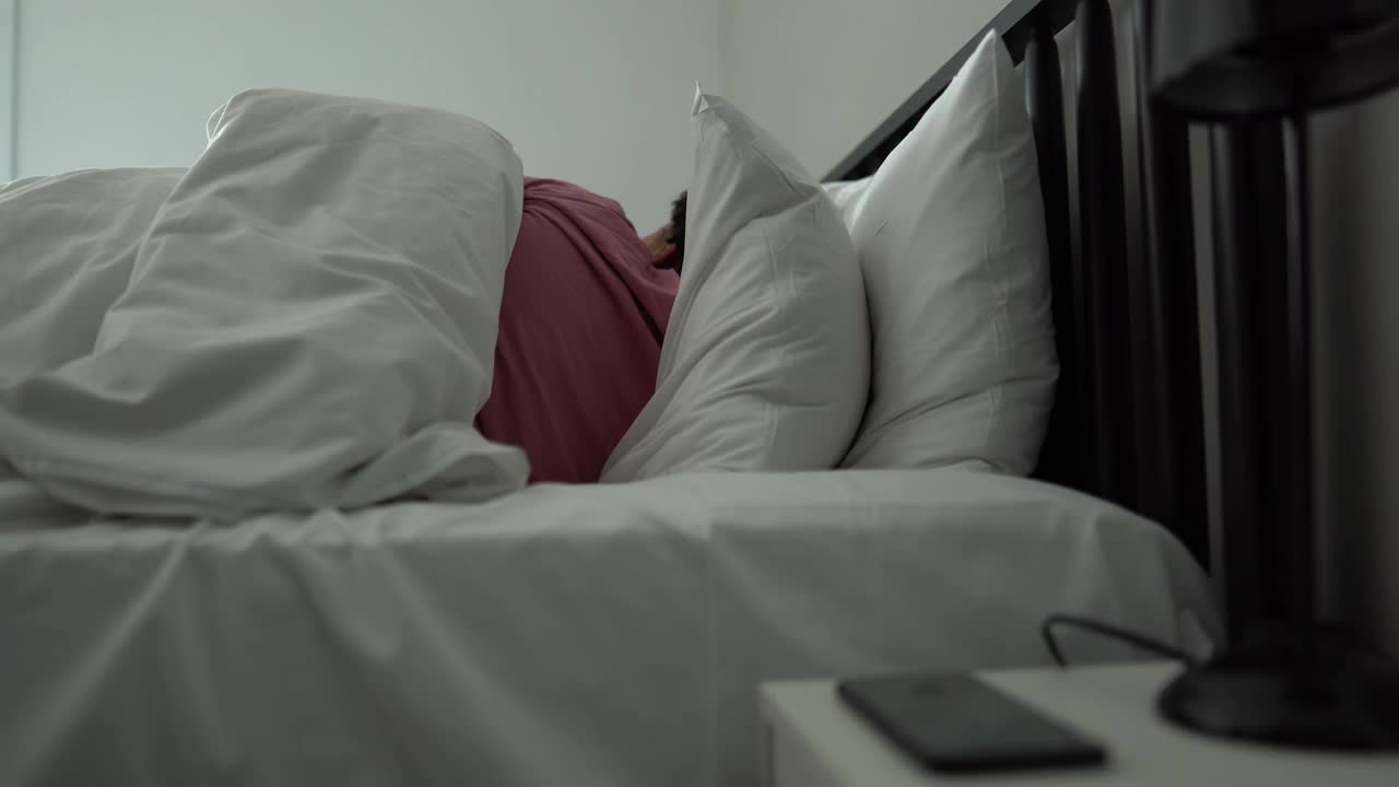 女人在床上醒来，查看智能手机视频下载