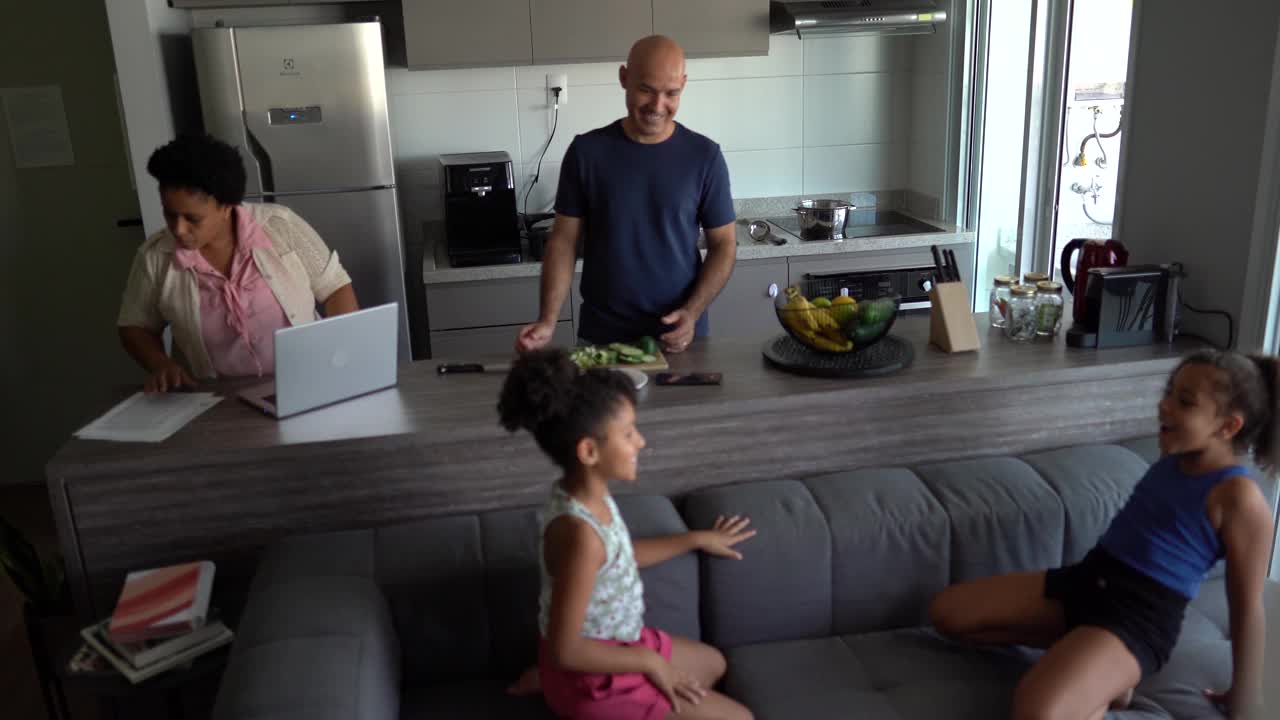 父母做饭/工作和女孩玩拍手游戏回家视频素材