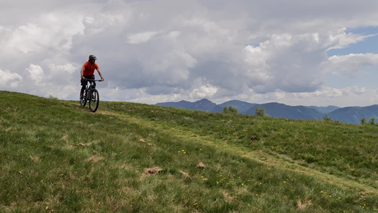 山地自行车手在高原上骑行的照片。一名男子骑着自行车下山视频素材
