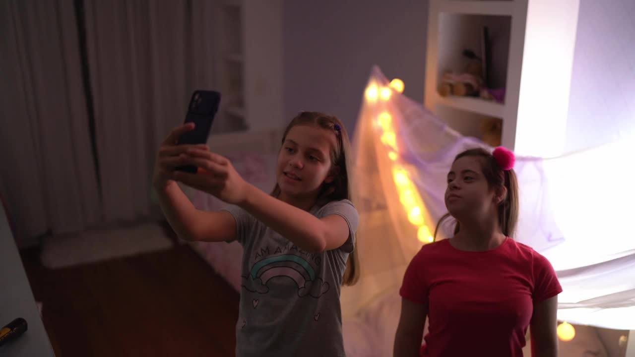 姐妹们在卧室里跳舞，在家里用智能手机拍摄——有特殊需要的女孩视频下载