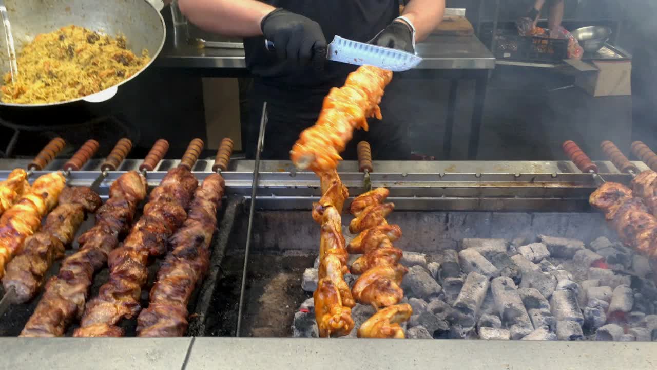 在户外用金属串在炭火上旋转烤肉串或烤肉串。在户外露天烧烤的腌制烤肉。视频素材