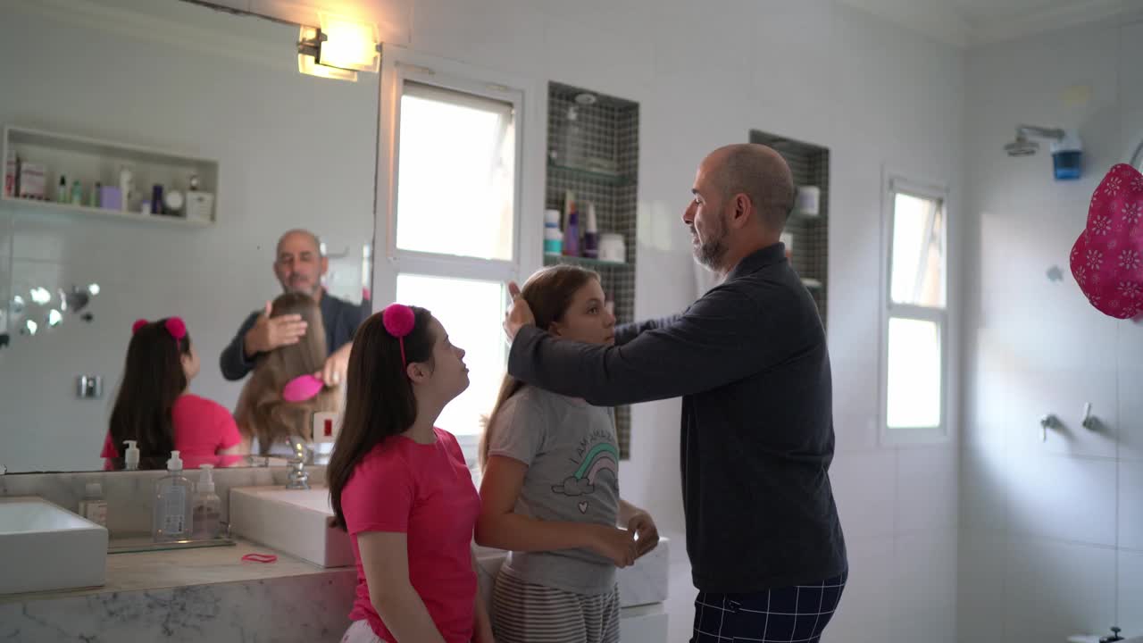 父亲早上在家给女儿做头发——包括一个有特殊需要的女孩视频素材