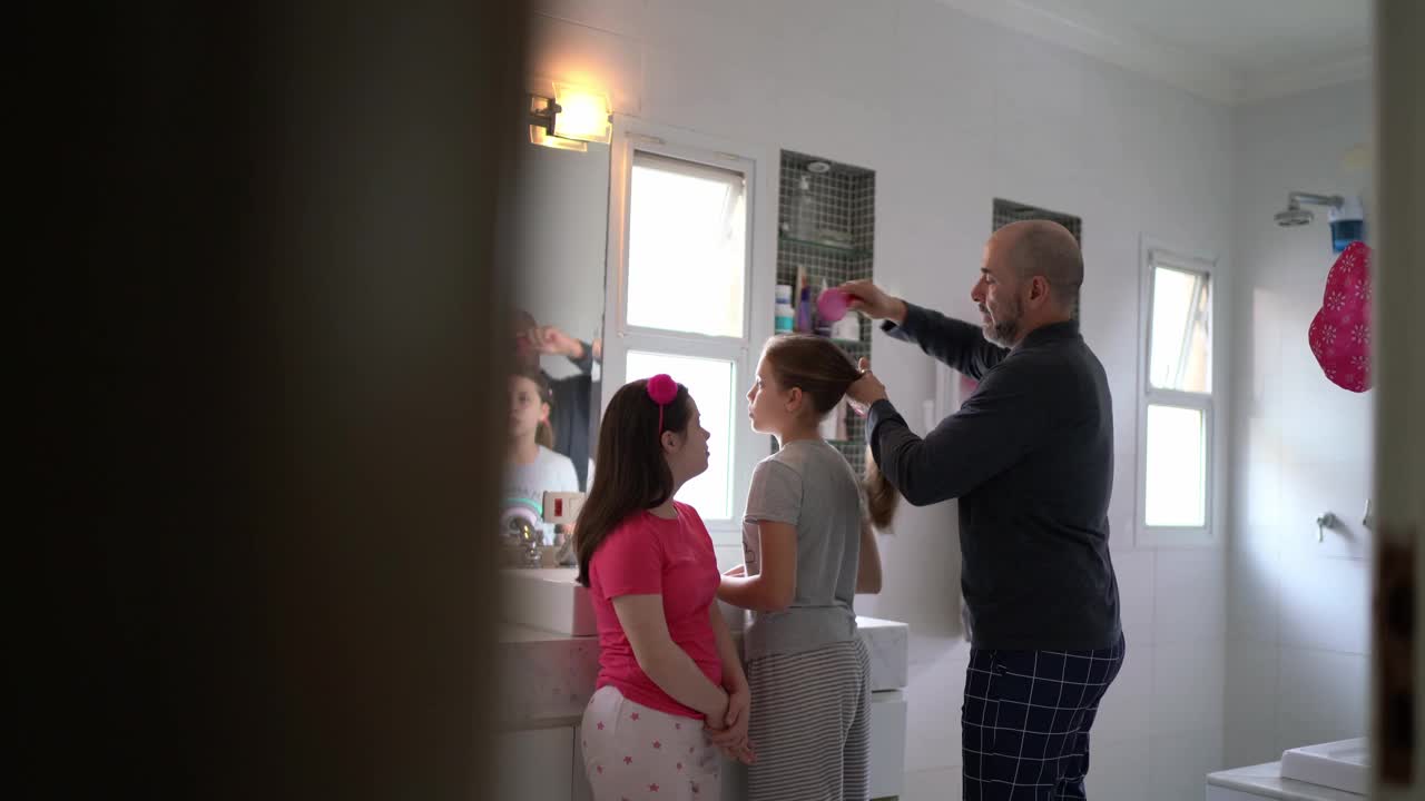 父亲早上在家给女儿做头发——包括一个有特殊需要的女孩视频素材