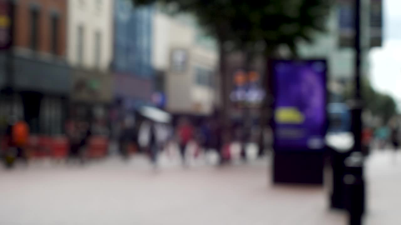 4K散焦匿名的人忙碌的购物者在购物的高街背景-模糊的通勤者在阳光明媚的一天。视频素材