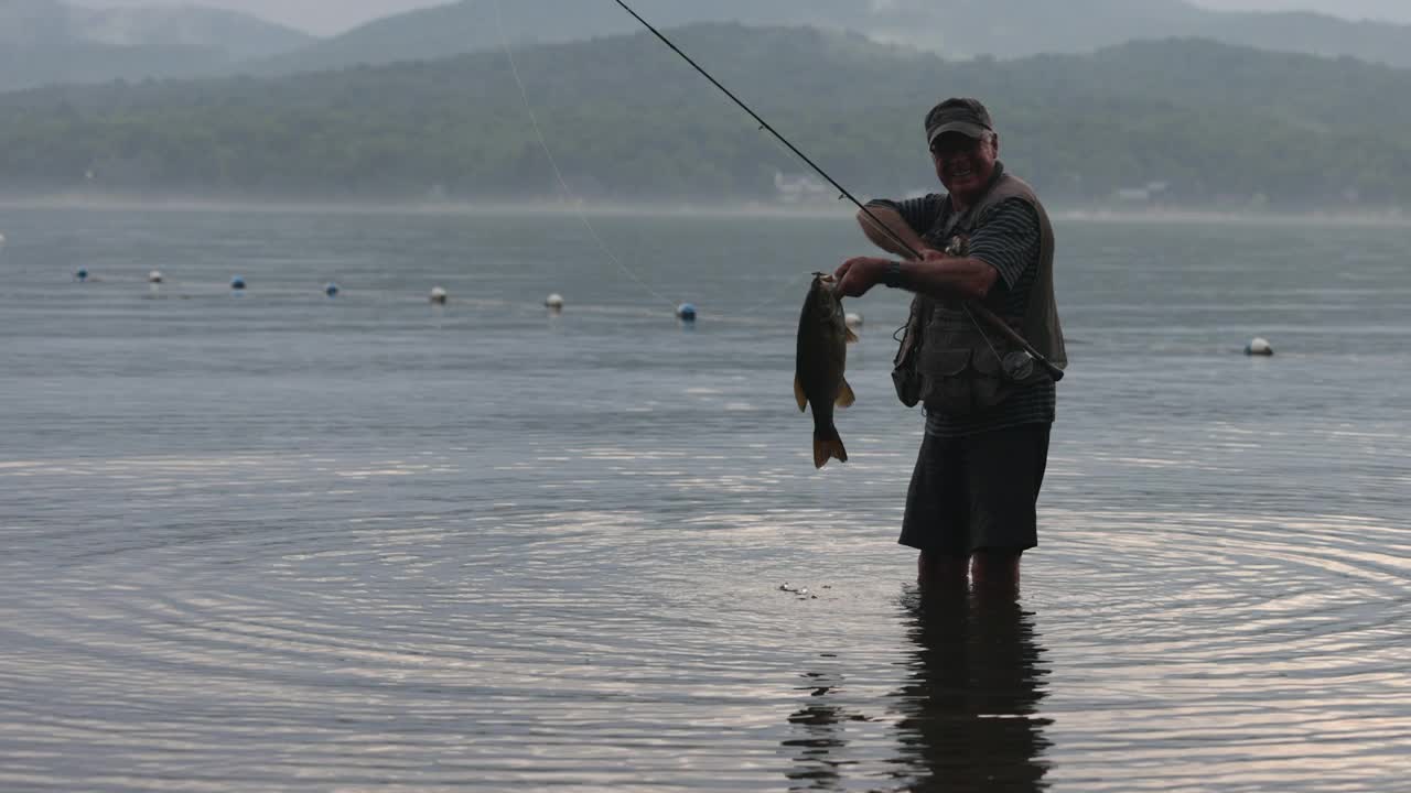 老男人在湖边飞钓和放鱼视频素材