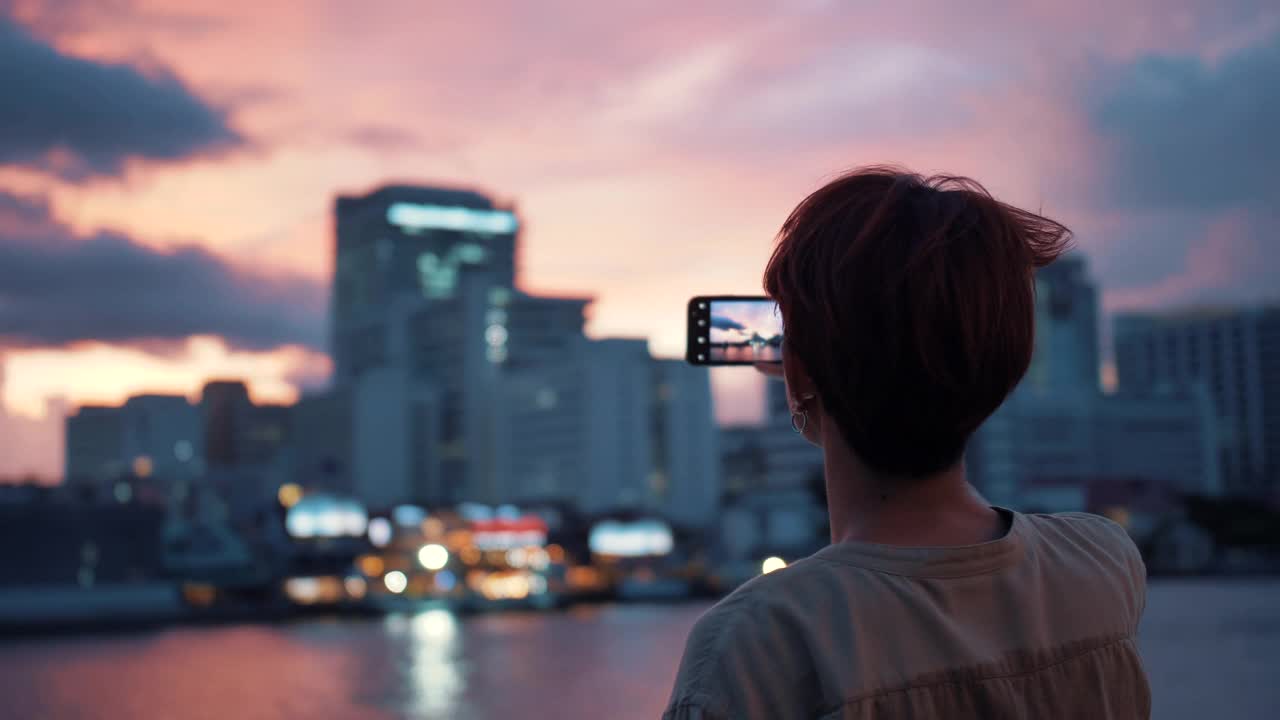 一名亚洲年轻人用智能手机拍照视频下载