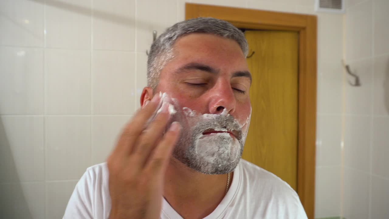 浴室里的一个男人在胡须上涂肥皂沫视频素材