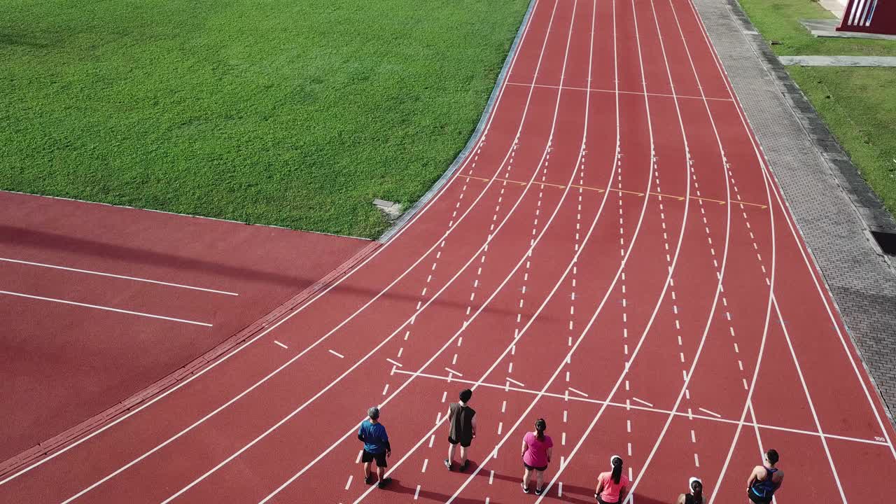 从无人机的角度看，亚洲华人运动员在田径场上排起了短跑队，并在早上跑向终点线视频下载