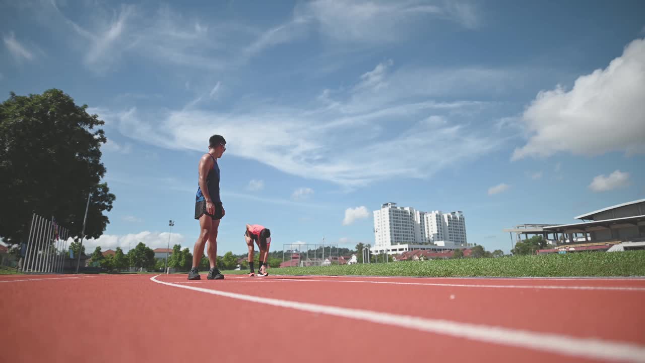 空气动力学的亚洲华裔男女运动员在田径场上冲刺，并在早上跑向终点线视频素材