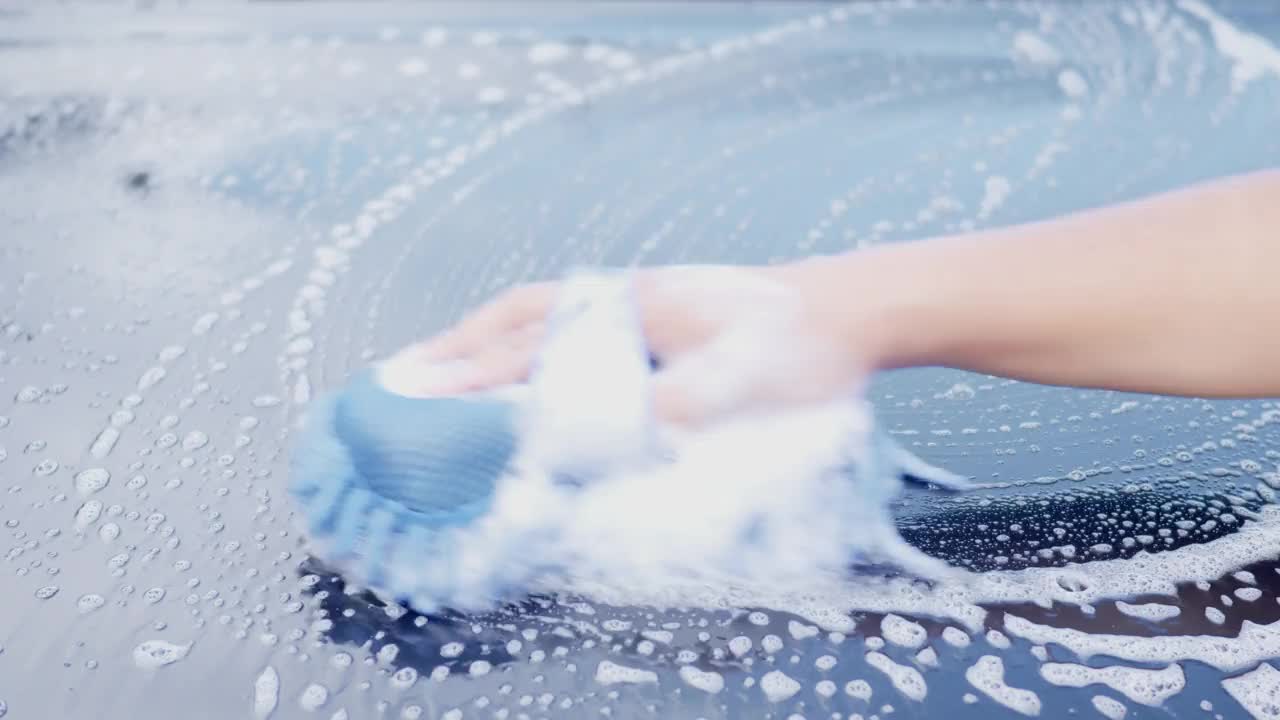 工人的手用洗发水泡沫布清洗黑色汽车的合金发动机盖视频素材