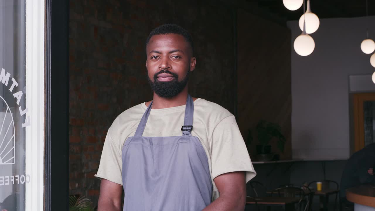 一个年轻帅气的咖啡师双臂交叉站在咖啡馆里的4k视频片段视频素材