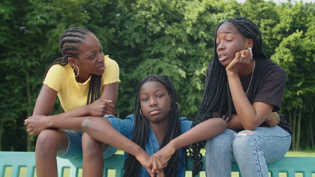 聊天可爱的黑人少女放松在夏季公园长椅上视频素材