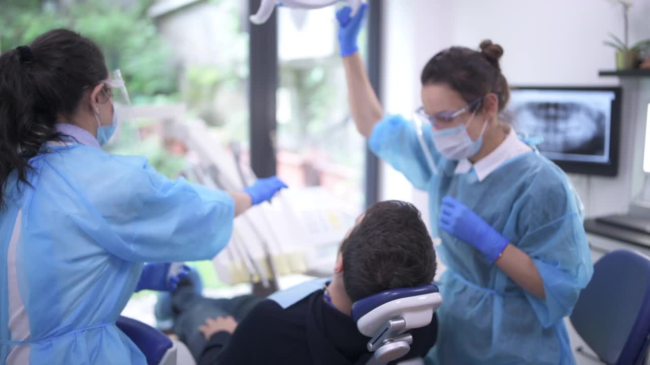 牙科医生和助理治疗病人在牙科诊所。视频下载