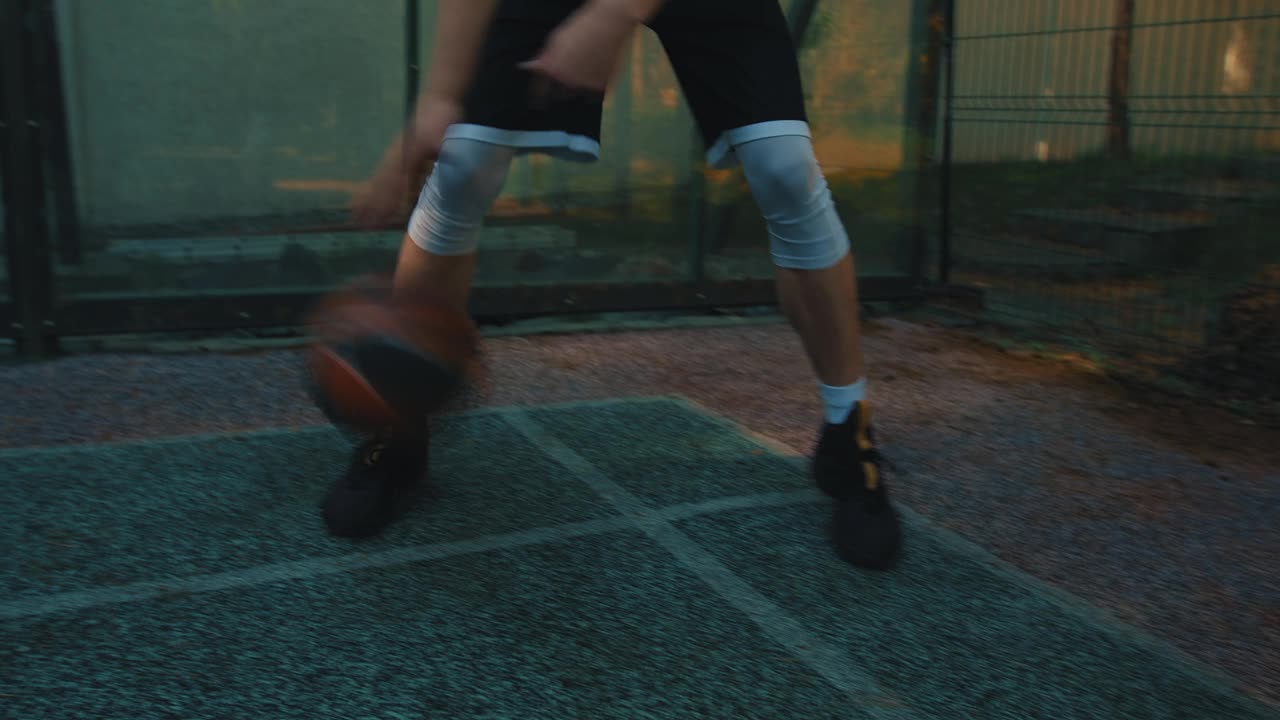 男子篮球运动员在篮球场上训练时，在两腿之间运球，得分视频下载