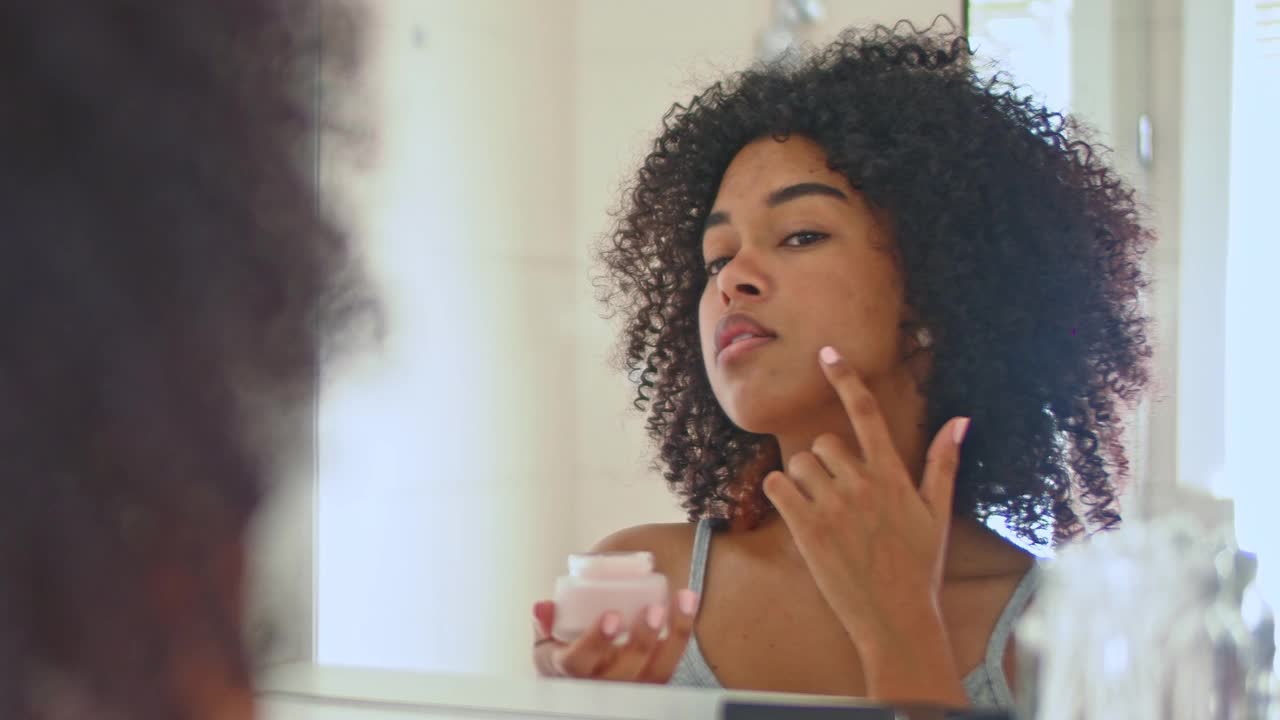 一名年轻女子在脸上涂抹润肤霜的4k视频片段视频素材