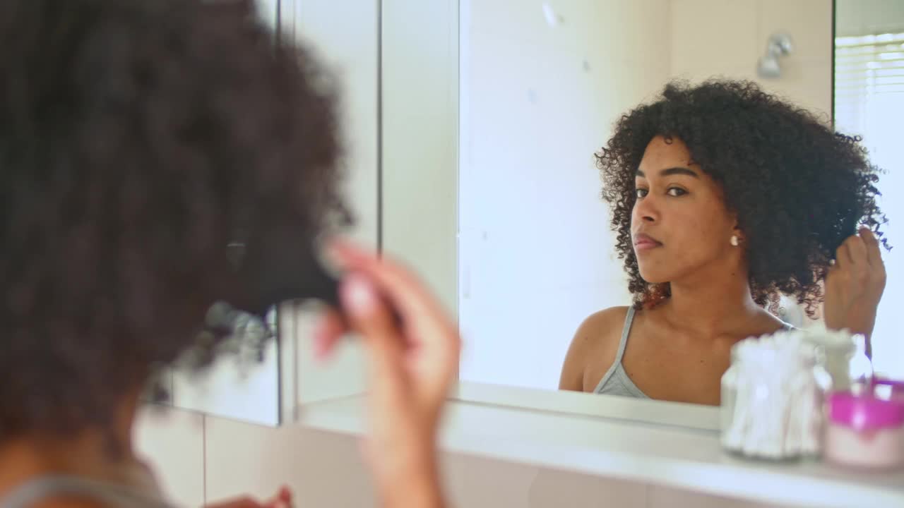 一名女子看着浴室镜子梳理头发的4k视频片段视频素材