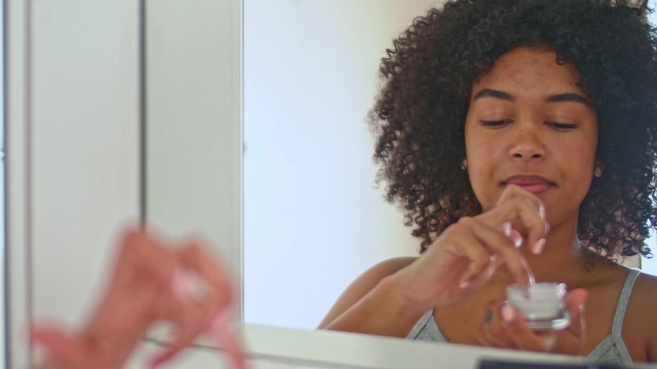 一名女子用眼霜看着浴室镜子的4k视频片段视频素材