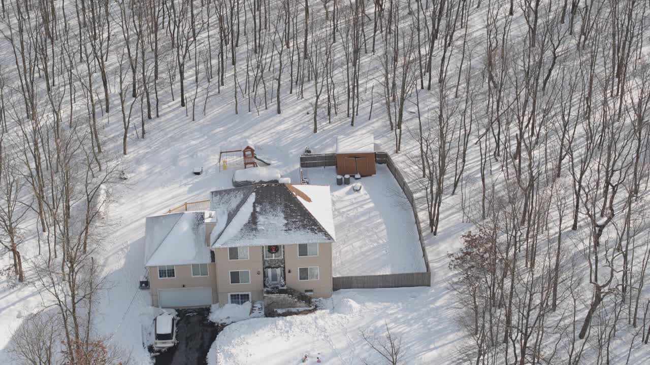 在一场冬季暴风雪后被雪覆盖的乡村社区的住宅。一辆车停在刚清理过的车道上。空中无人机视频。视频下载