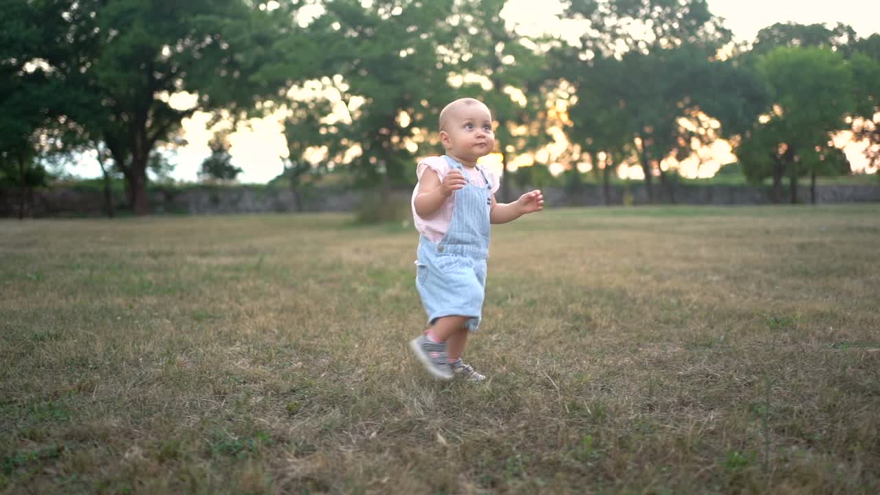 可爱的小女孩兴奋地在草地上奔跑，学习如何走路视频下载