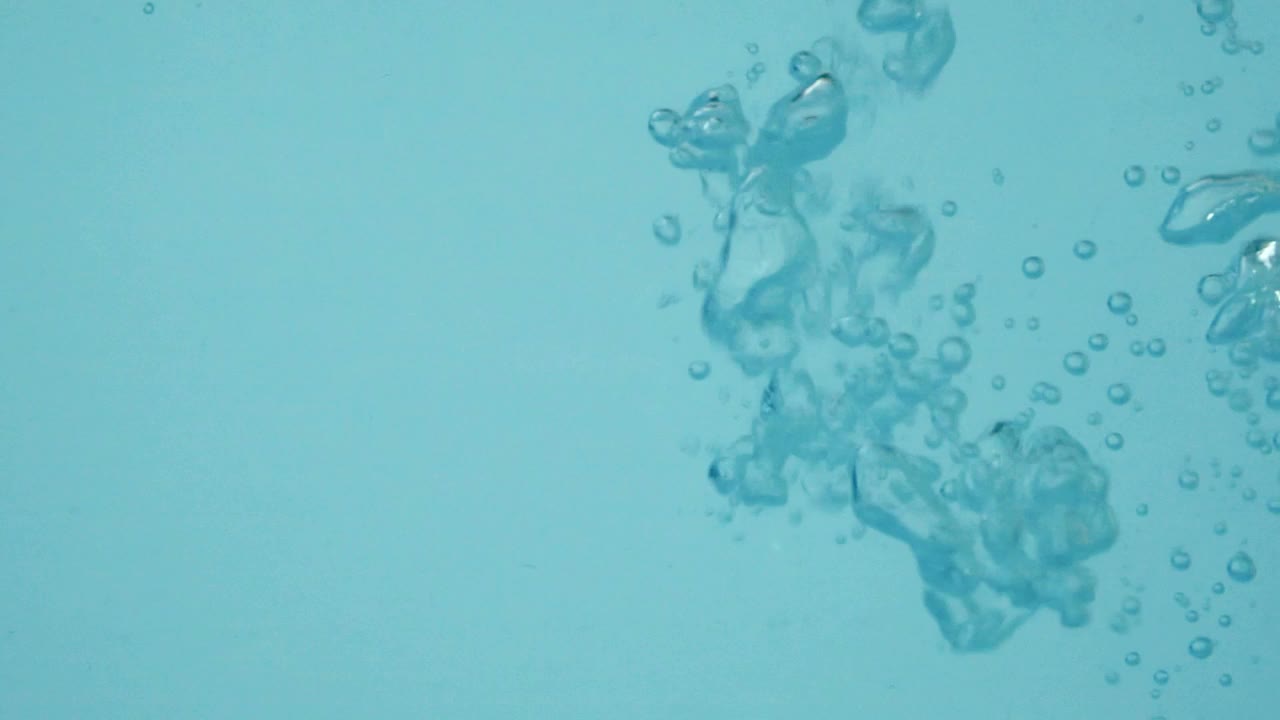 近距离慢动作的空气气泡在纯净透明的蓝色水，创造氧气气泡和飞溅视频下载