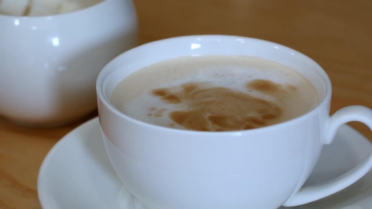 特写白糖落入一杯黑咖啡与牛奶，拿铁，卡布奇诺。咖啡饮料。视频素材