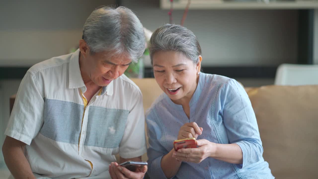 快乐的亚洲华人祖父母使用电话，在客厅愉快地交谈视频素材
