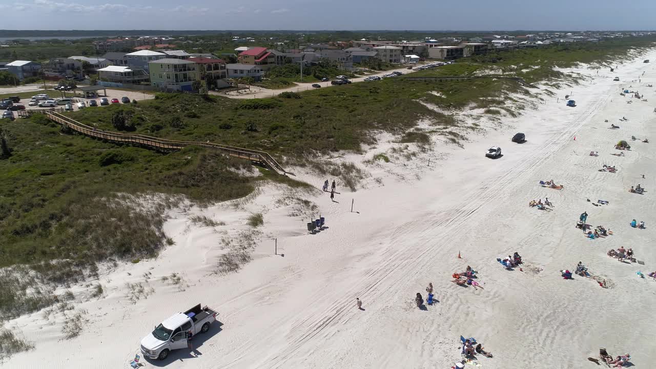 佛罗里达州的许多海滩通常允许汽车通行。佛罗里达圣奥古斯丁郊区住宅区的鸟瞰图，沿着大西洋的沙滩延伸，在狭窄的沙丘后面覆盖着灌木和植物。视频下载