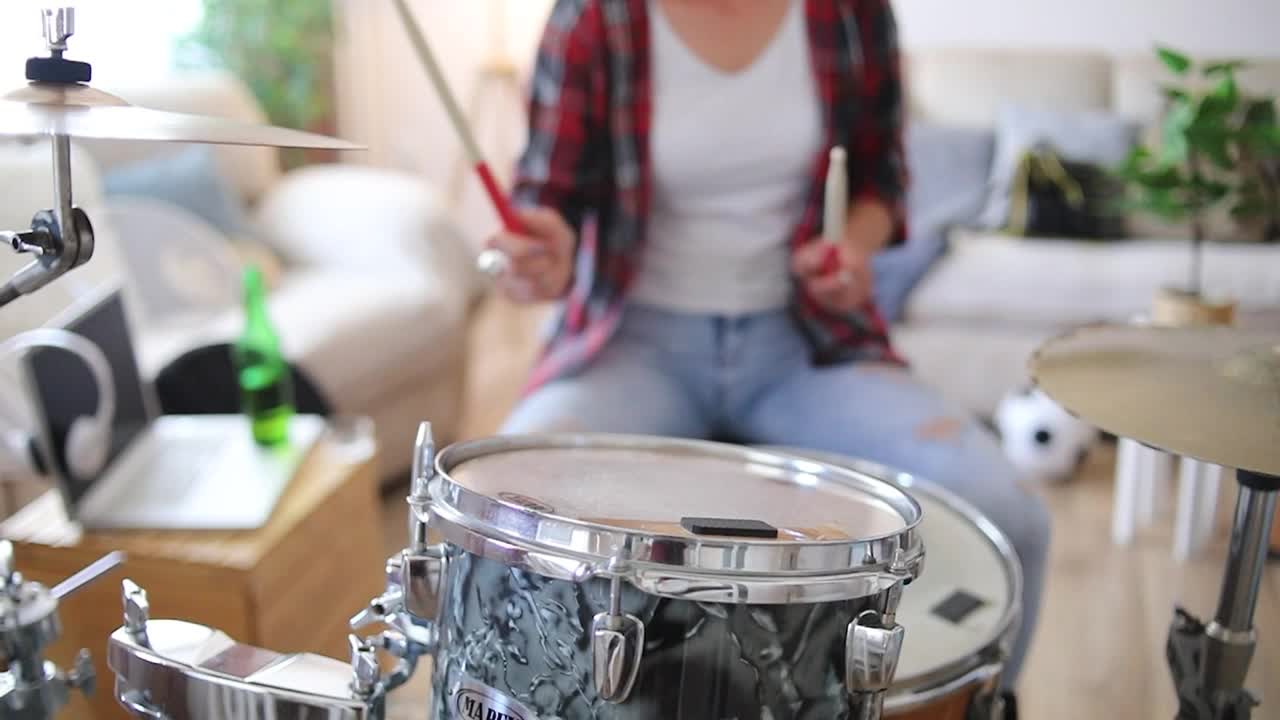 一个年轻女子在她的客厅里练习原声鼓。头敲。视频下载