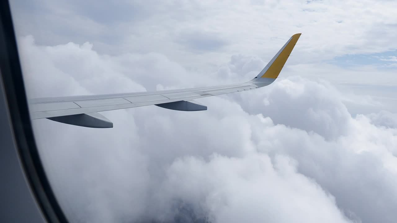 一架飞机的机翼从飞机窗口穿过天空的云层。视频素材