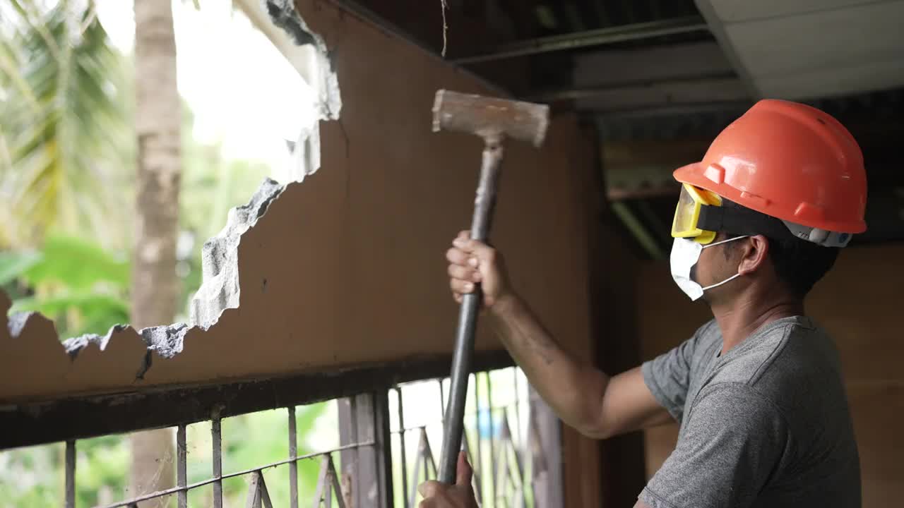建筑工人戴着防护面具，用大锤拆墙视频素材