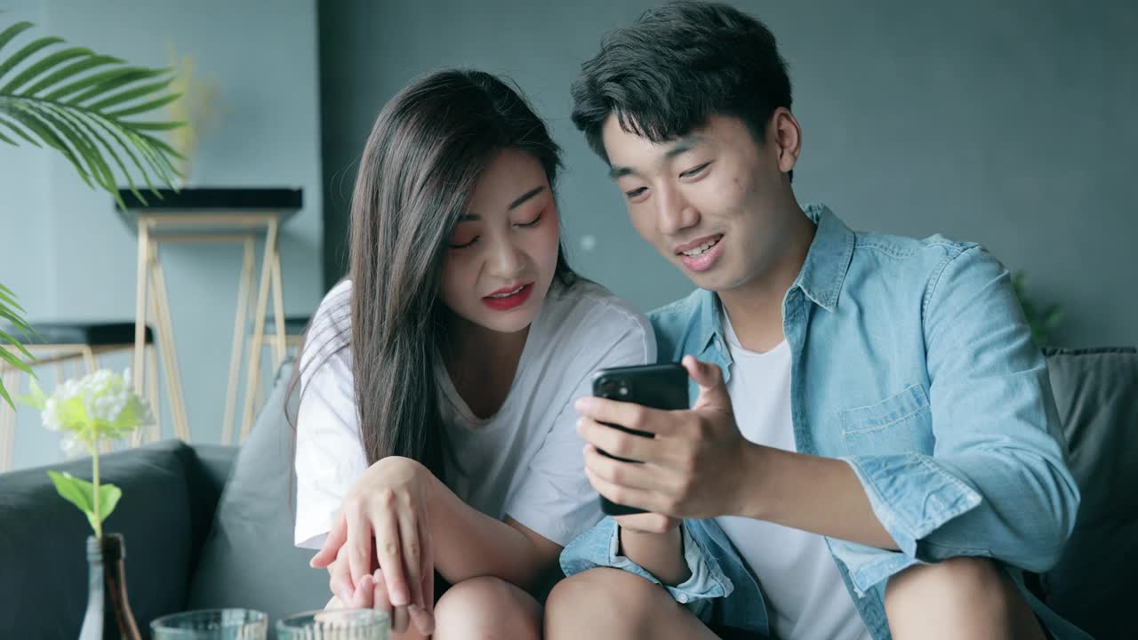 快乐的年轻夫妇看着手机视频素材