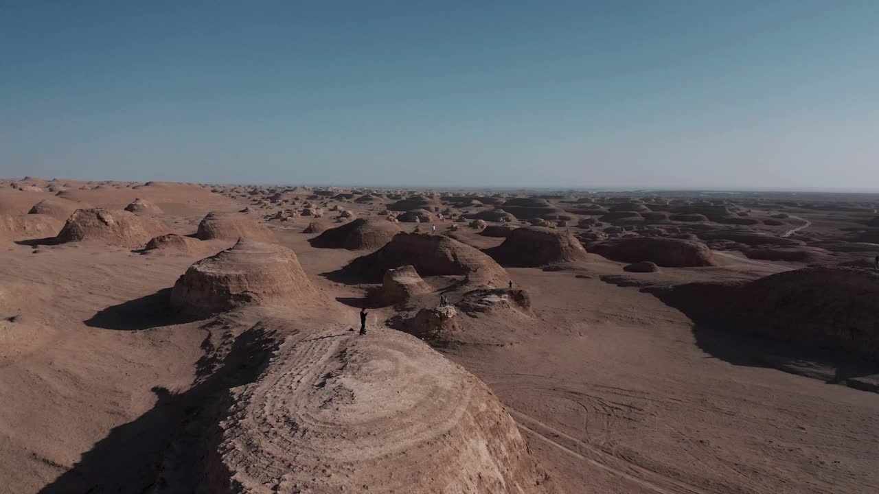 无人机拍摄的人们站在雅丹大地形上的视频视频下载