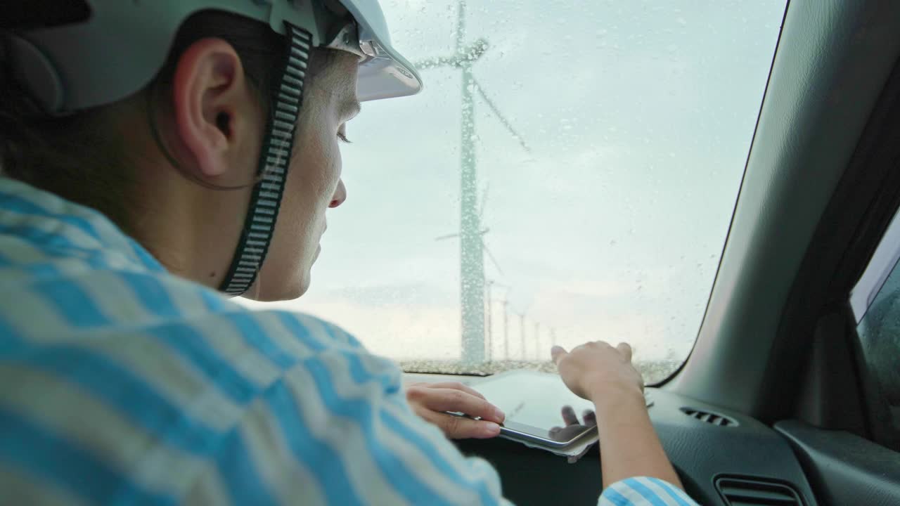 风力涡轮机工程师在雨天在汽车里工作。可再生能源系统。视频素材