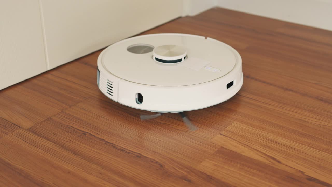 白色机器人真空吸尘器在强化地板清洁灰尘在家里。视频素材