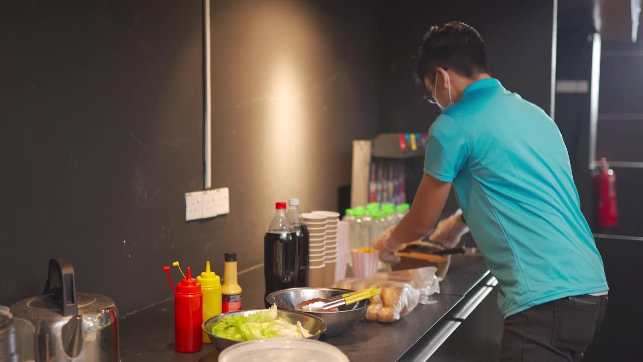 一名中国快餐工人在娱乐大楼的小卖部准备热狗三明治视频素材