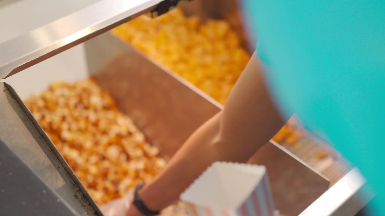 在娱乐大楼里的租界小卖部，快餐店工作人员用勺子把爆米花塞进纸桶里视频下载