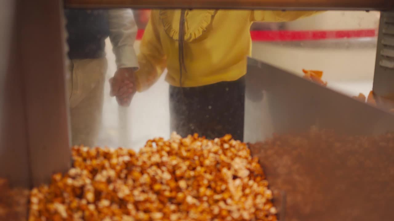 在娱乐大楼的小卖部，亚洲华人祖父孙女看着快餐店工人把爆米花塞进纸桶里视频素材