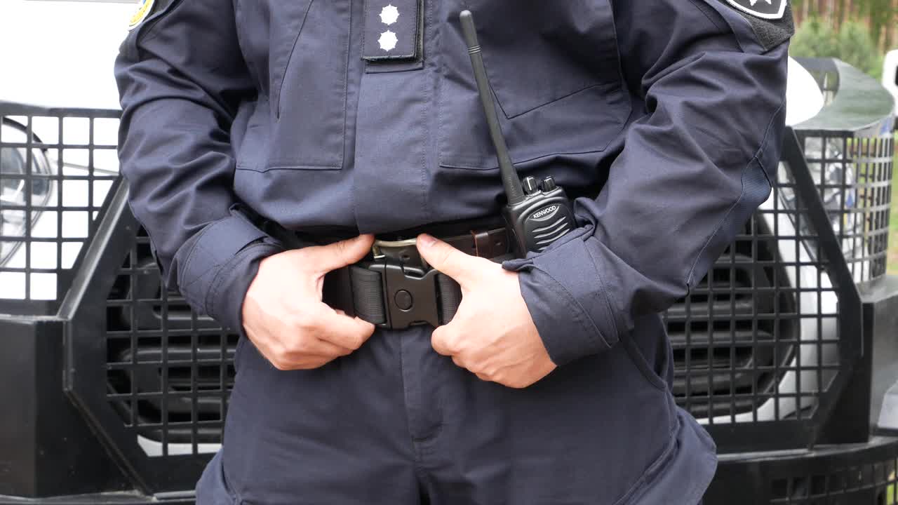一名警察站在一辆警车后面，抓着一个皮套。视频下载