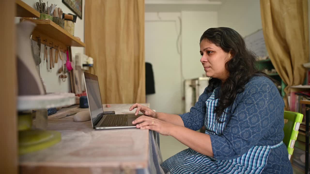 女陶艺师工作在笔记本电脑在她的工作室视频素材