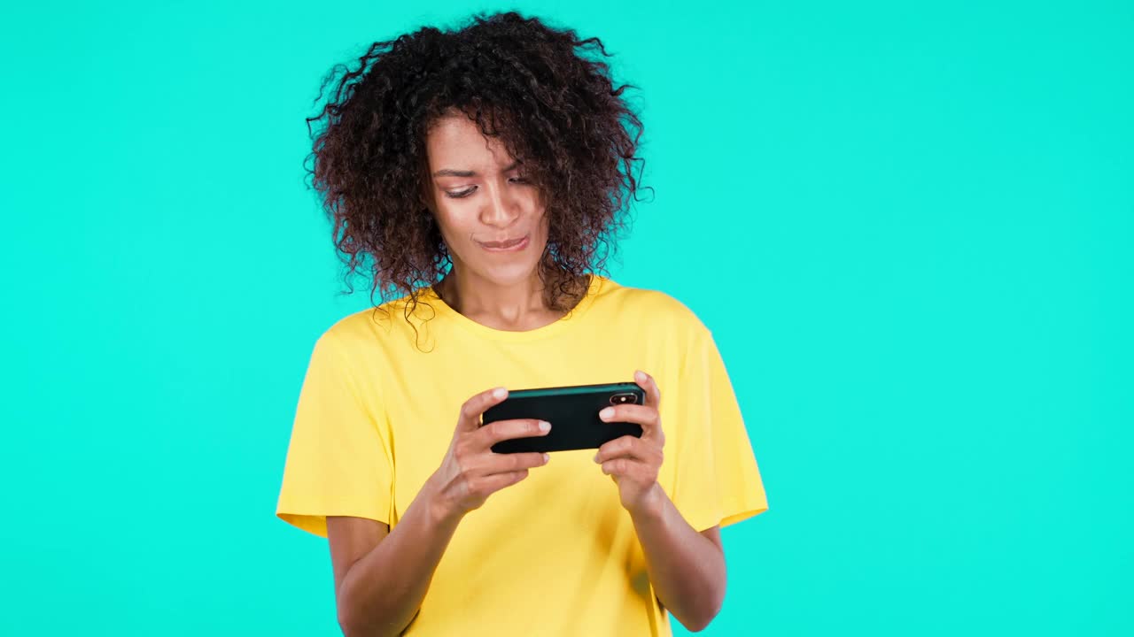 非裔美国女性在工作室墙上玩智能手机游戏。使用现代技术——应用程序，社交网络，娱乐内容视频素材