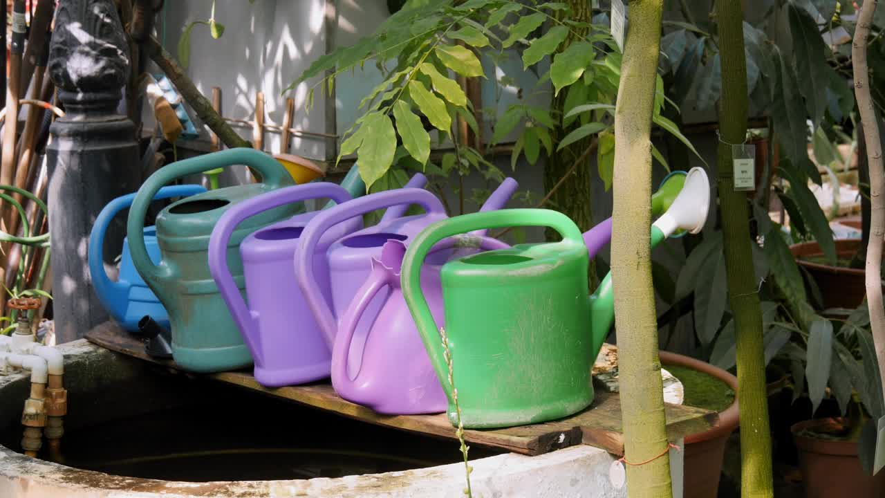 五彩缤纷的喷壶放在花园里的井或喷泉上。视频下载