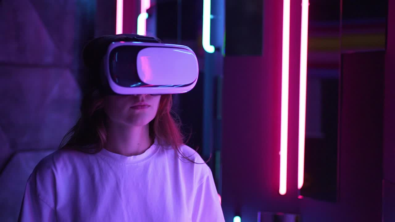 虚拟现实的体验。在霓虹灯下戴着虚拟现实头盔的年轻女子视频素材