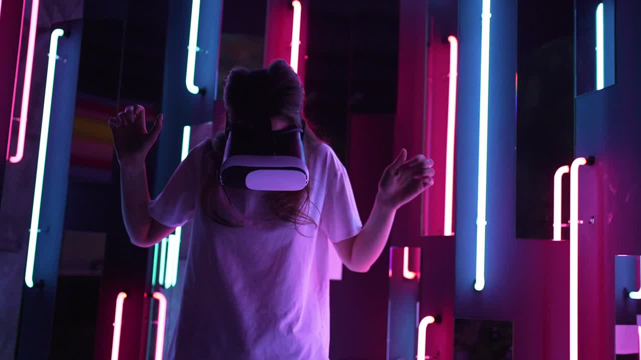 一位戴着耳机的年轻女性正在探索VR。霓虹灯。快乐的娱乐新体验视频素材