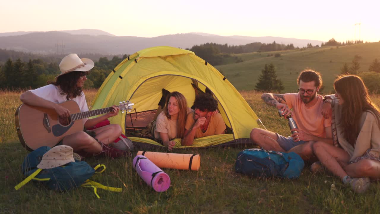 年轻人在一起露营，听朋友弹原声吉他。视频素材
