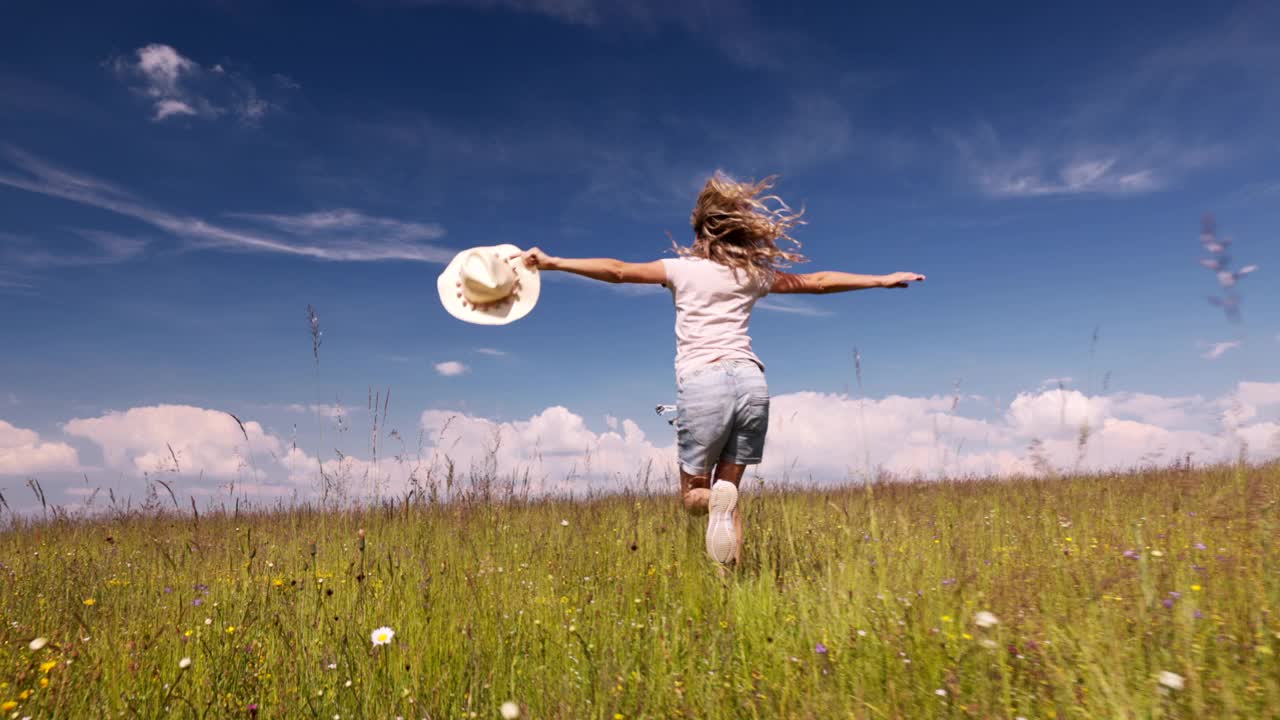 无忧无虑的年轻女子独自在草地上奔跑。视频下载