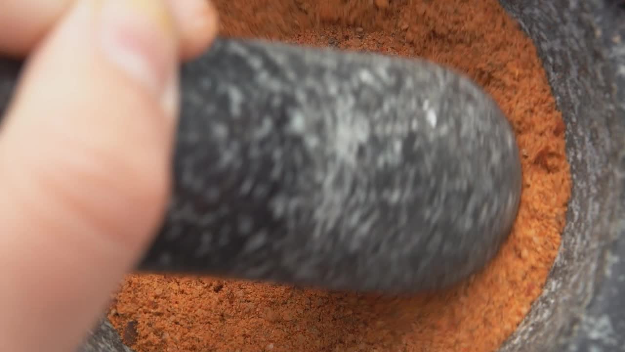 超级特写的重型杵研磨和混合香料在一个灰色的石头臼视频下载