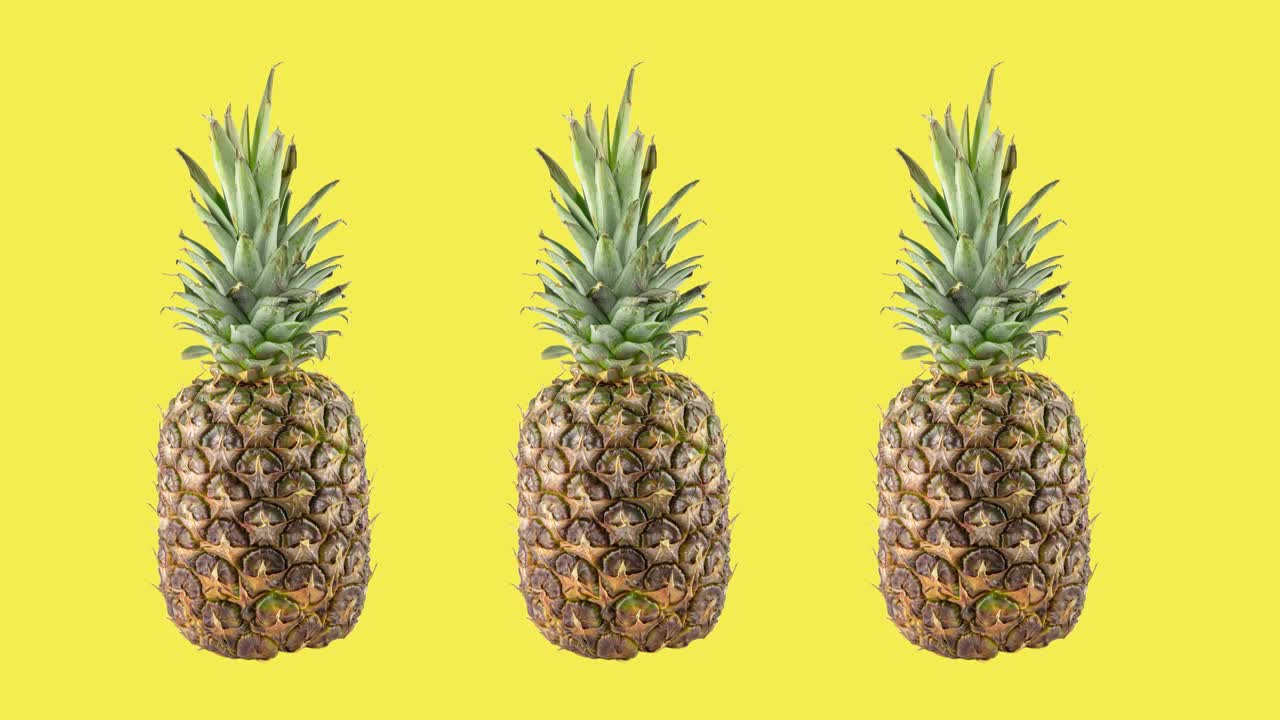 定格动画与三个成熟的新鲜菠萝旋转在黄色的背景。旅行的概念与复制空间视频下载