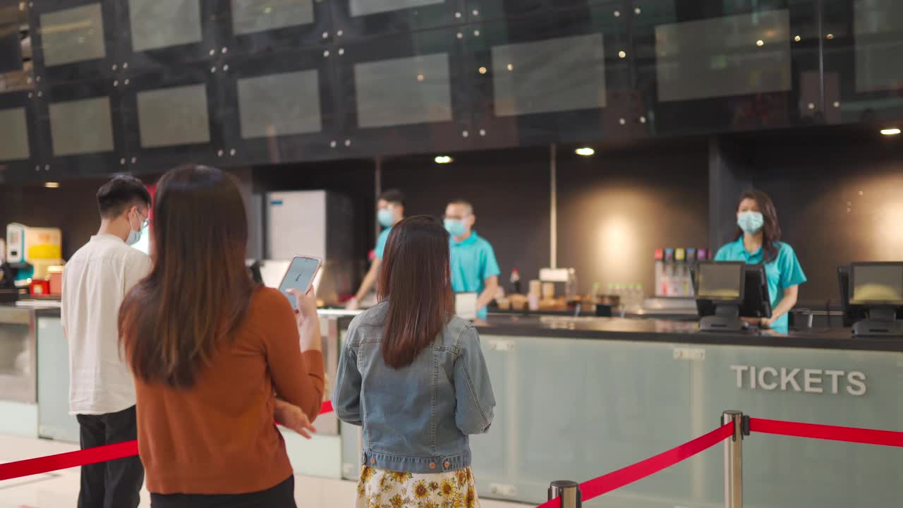 社交距离后视镜亚洲华人人群排队购买电影票和零食在电影院电影院与新常态的实践SOP视频素材