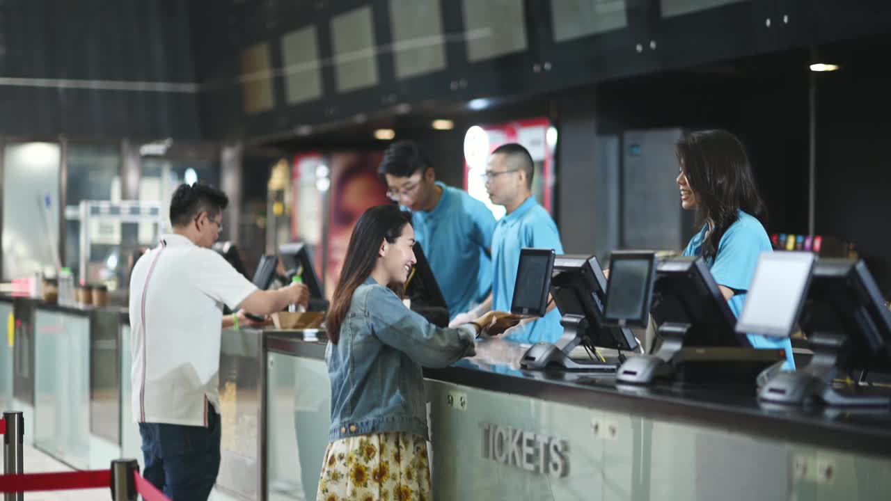 亚洲华人女性顾客在电影院售票处购买电影票视频下载